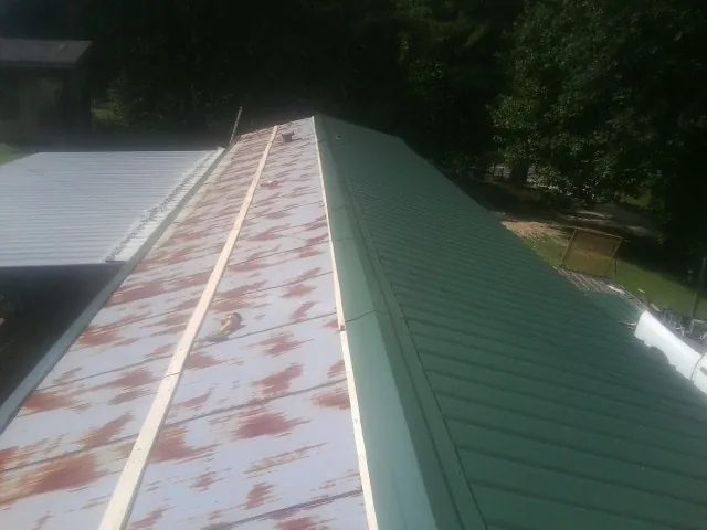 Old rusted panels beside newly installed green metal roofing — Wind Damage Roof Repair by Roofing Brothers in Albertville