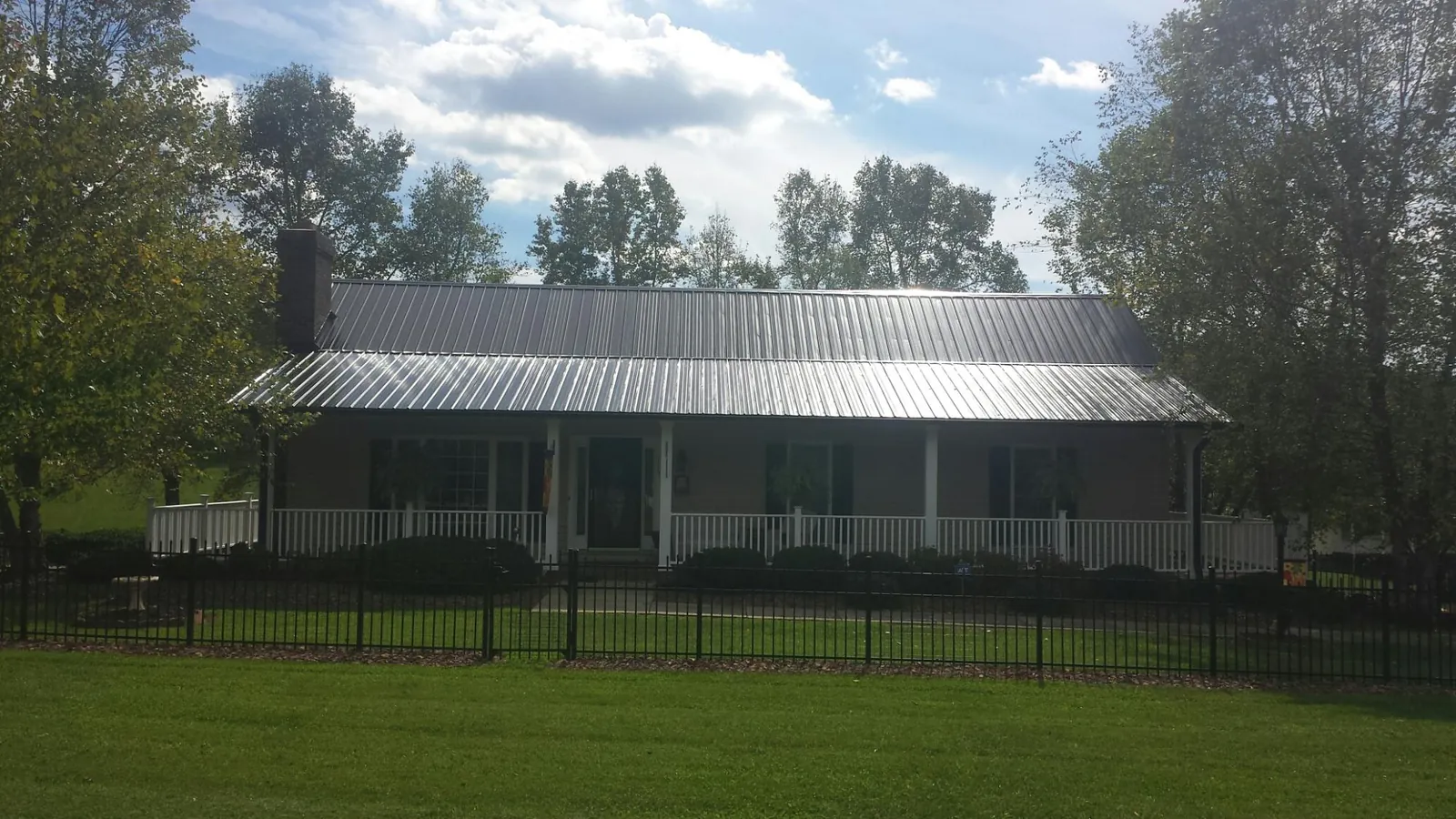 Gray metal roof on a brick ranch with a full width front porch — Gutter Guard Installation work by our crew in Albertville