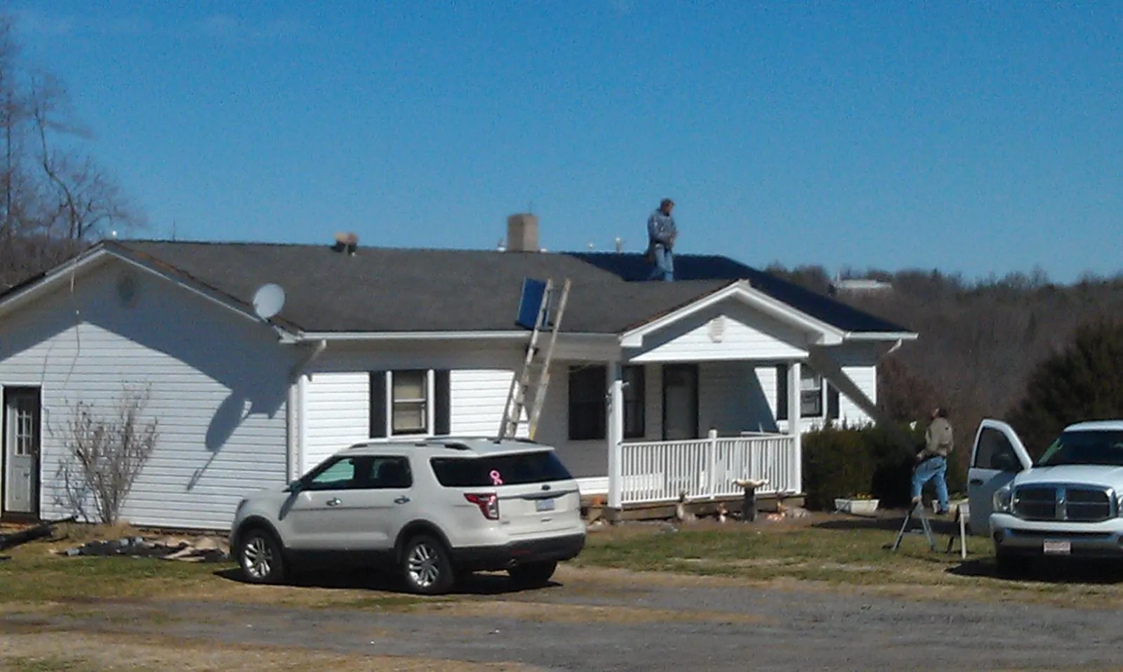 Roofers stripping shingles from a white ranch house roof in Albertville